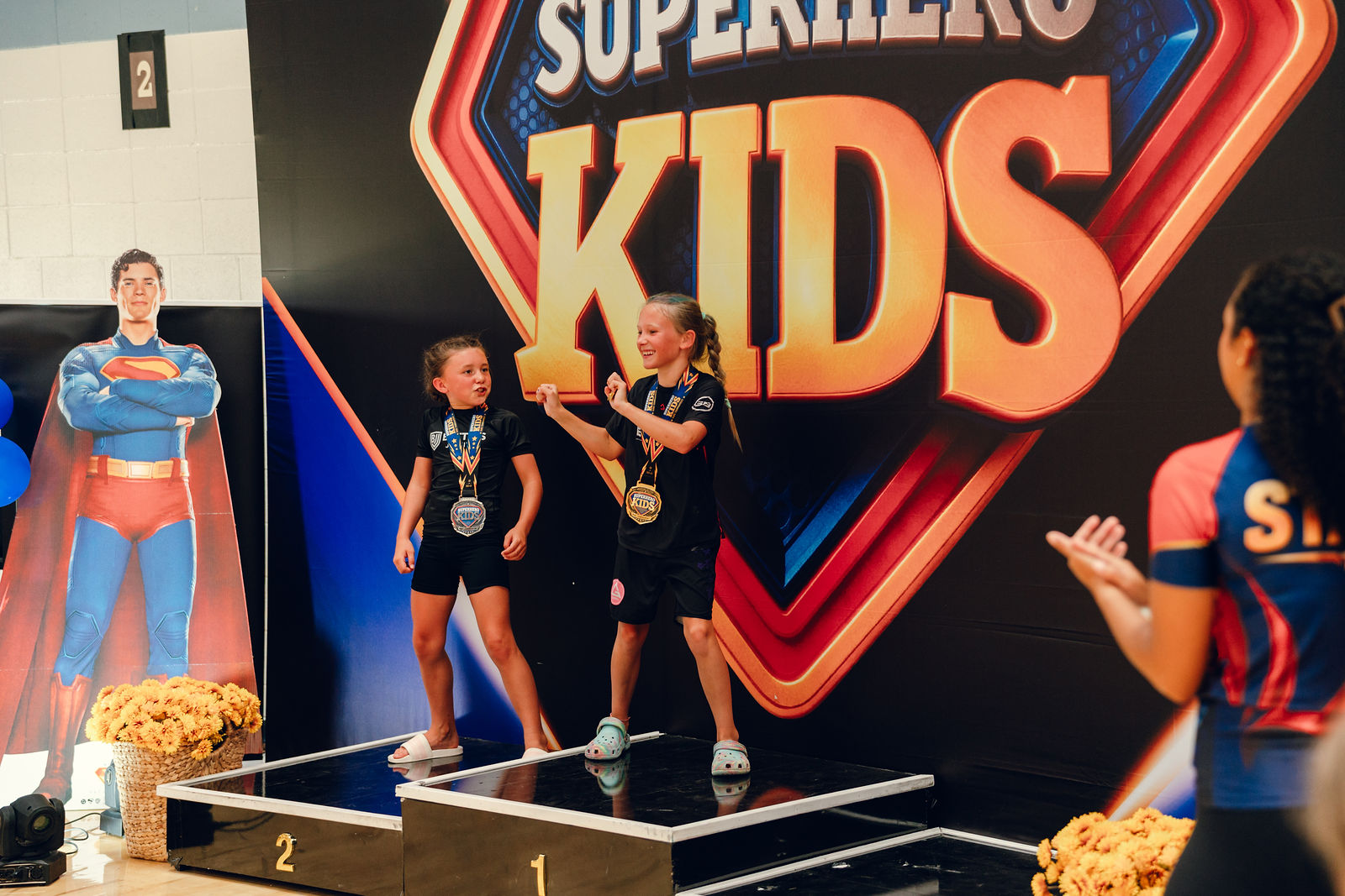 Girls celebrating together on the podium at Superhero Kids Nampa
