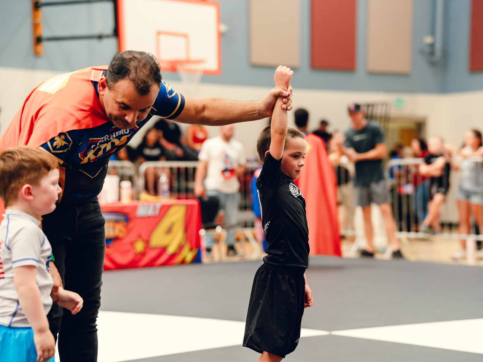 A referee raises the hand of a young Jiu-Jitsu athlete after his match at Superhero Kids Nampa