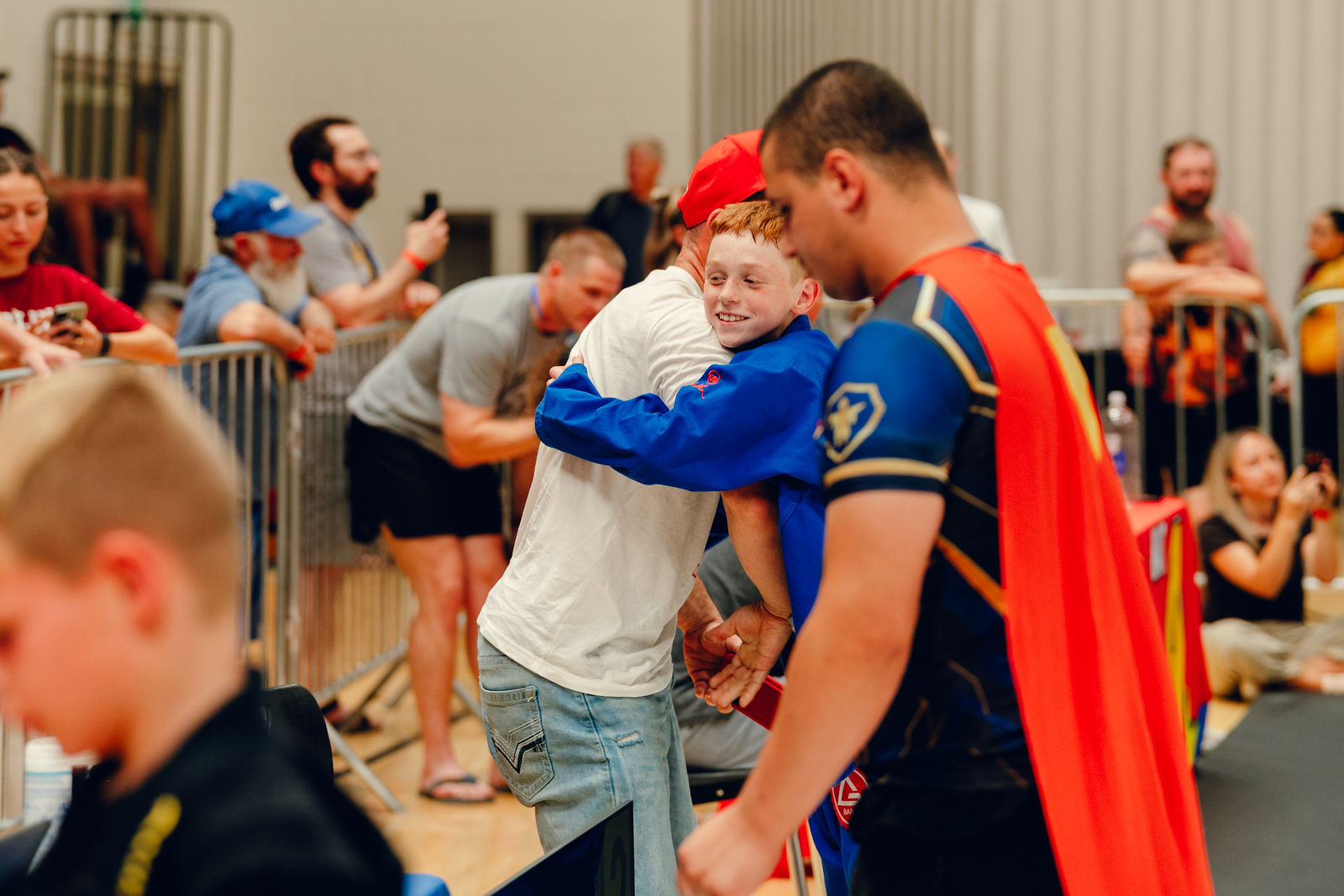 A coach hugging a young athlete after a match at Superhero Kids Nampa